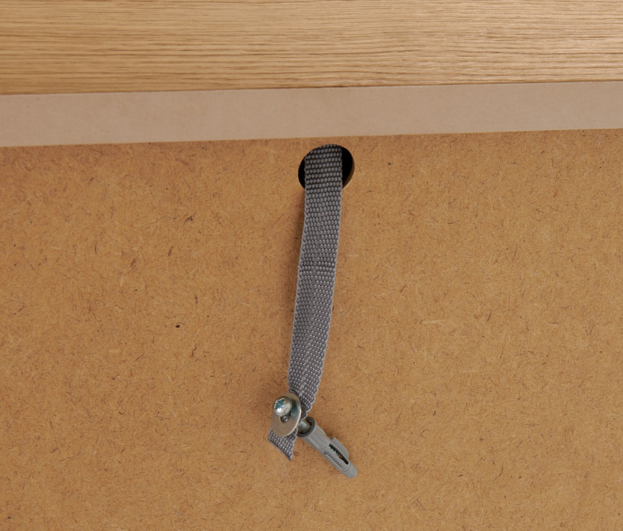 Detail der Befestigung des Schranks an der Wand mit Schraube, Dübel und Gurt.