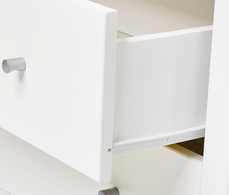 Detailaufnahme eines weißen Schranks mit Schubladen, wobei eine Schublade teilweise geöffnet ist.