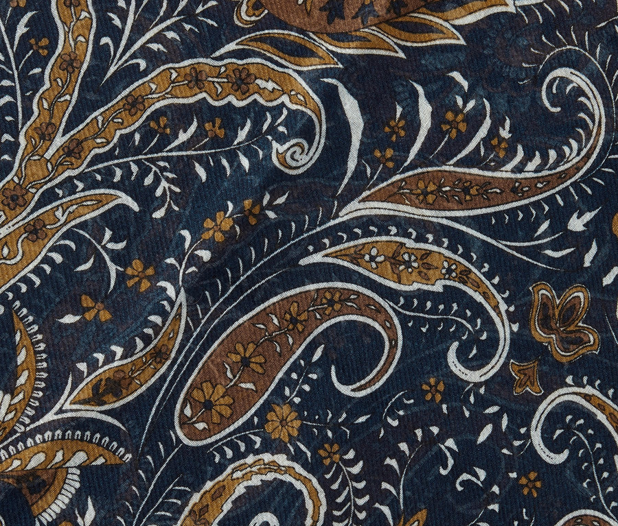 Nahaufnahme eines gewebten Schals mit braunem und weißem Paisleymuster auf dunkelblauem Grund.
