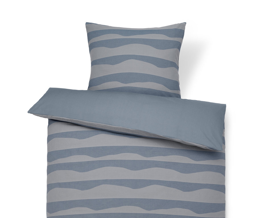 Jacquard-Bettwäsche mit blauen Wellen auf einem Bett.