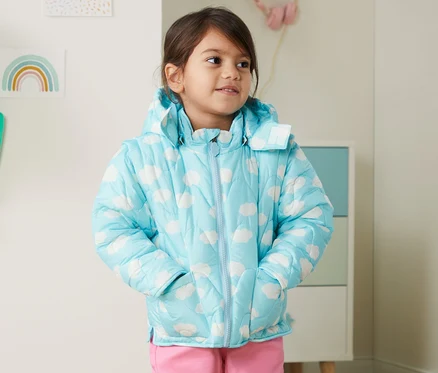 Mädchen mit Steppjacke aus recyceltem Material mit Händen in den Taschen.