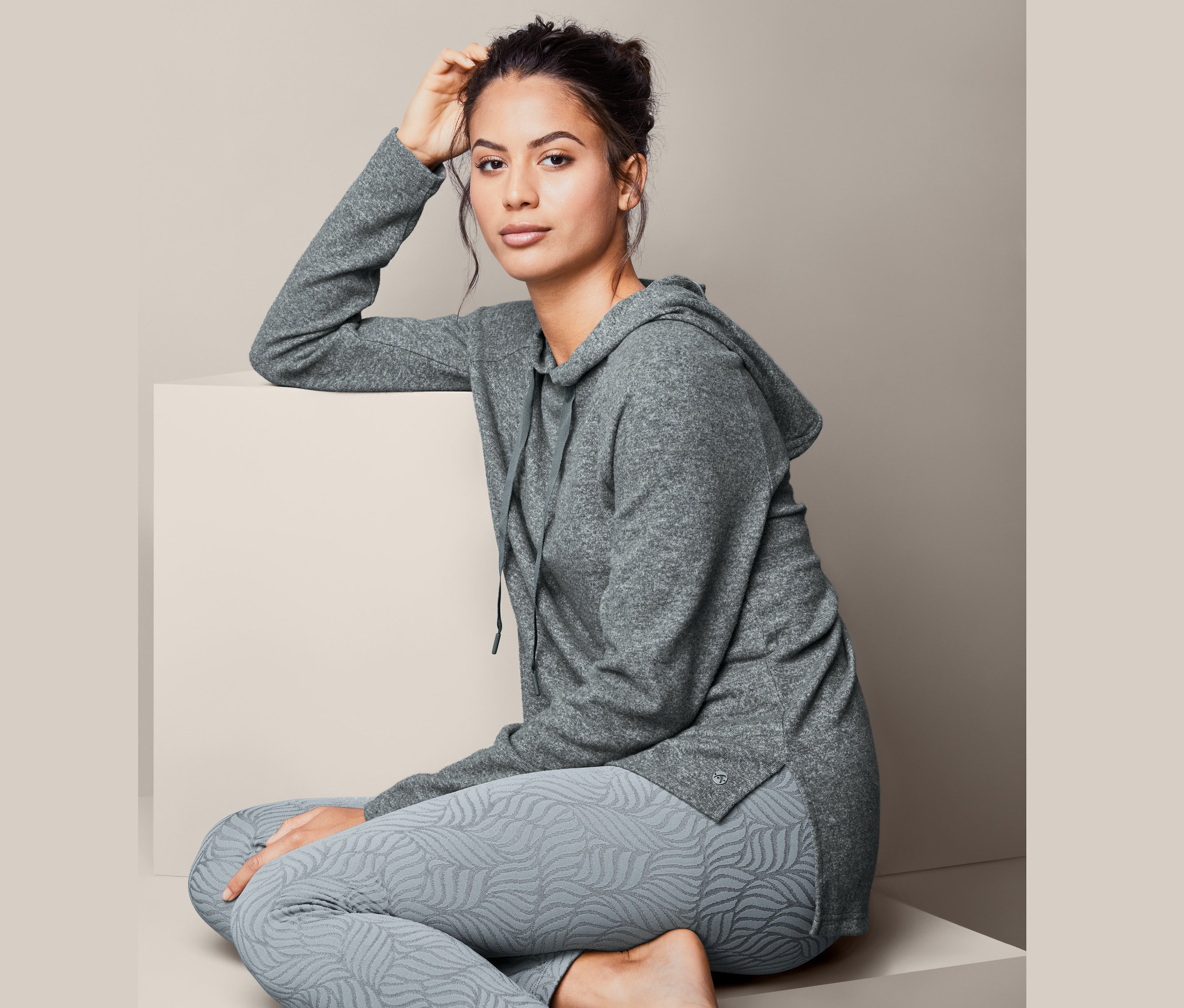 Frau sitzt und posiert in grauem Relaxshirt.