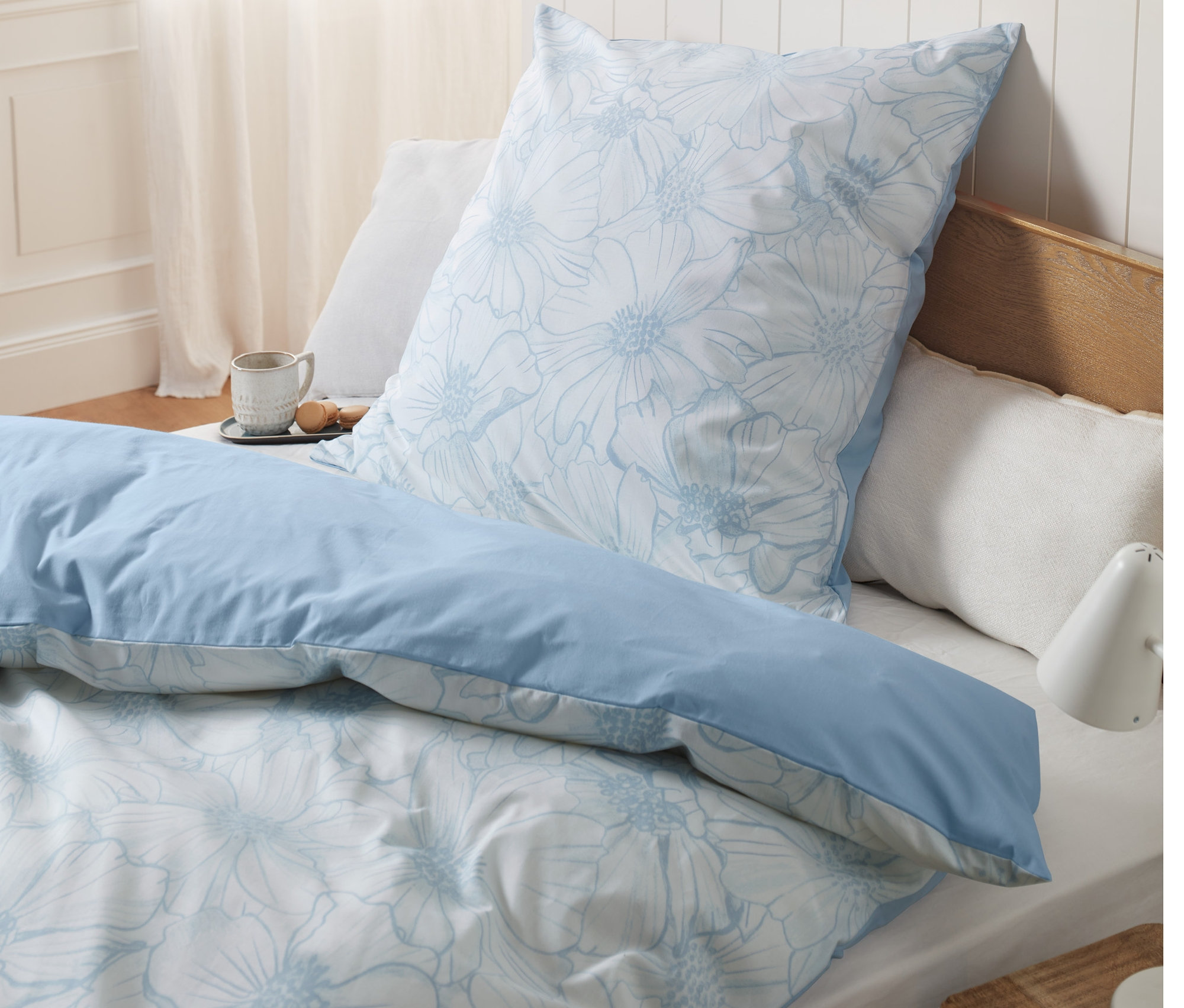 Blaues Renforcé-Bettwäsche-Set mit Blumenmuster auf einem Bett.