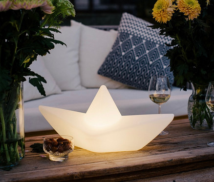 Eine Goodnight Light LED-Leuchte »Boot« steht auf einem Holztisch.