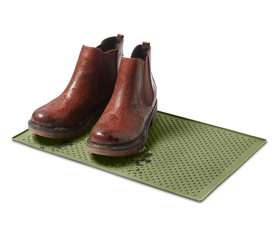 Zwei braune Stiefel stehen auf einem grünen Futternapf-Untersetzer.