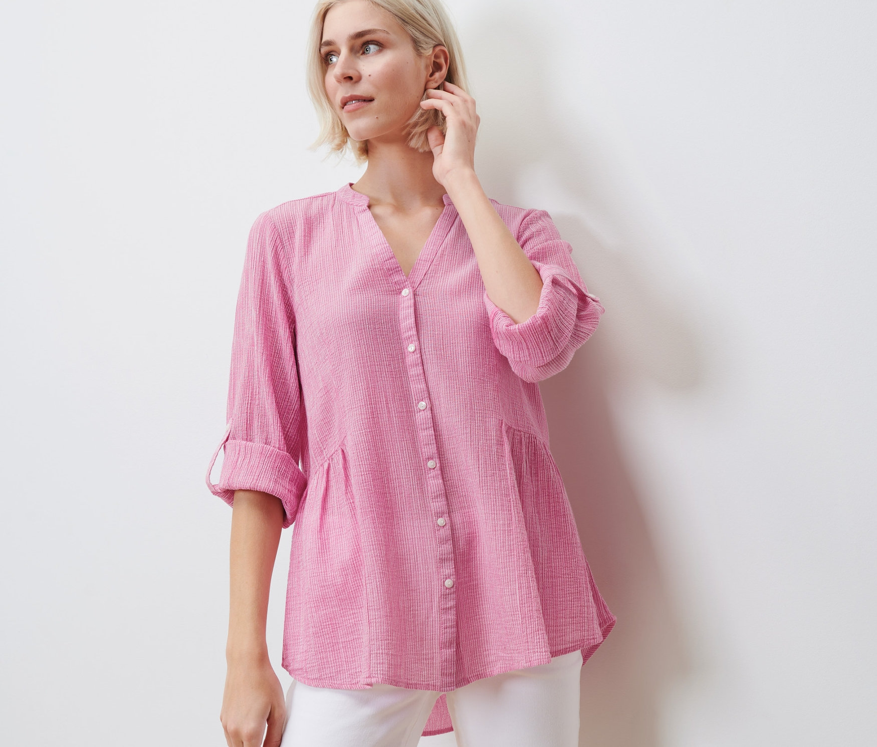 Frau posiert in gestreifter Longtunika und weißen Hosen.