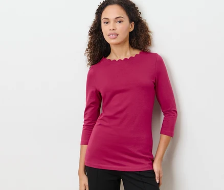 Frau posiert in himbeerrotem Shirt mit 3/4-Arm.