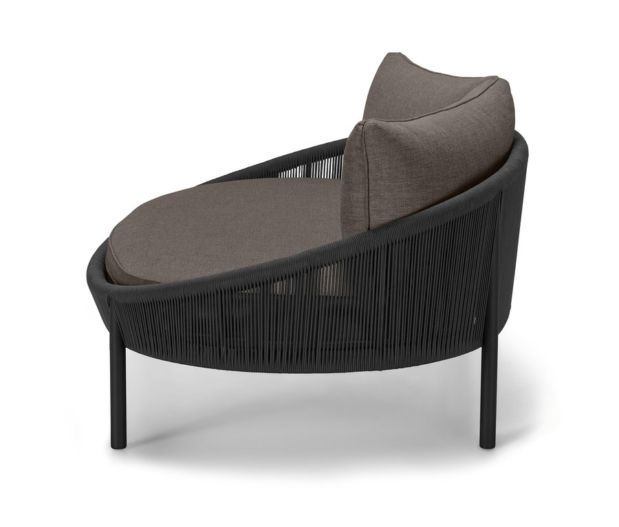 Seitenansicht des Daybeds »Jara« mit Textilgeflecht, runder Sitzfläche und Kissen.