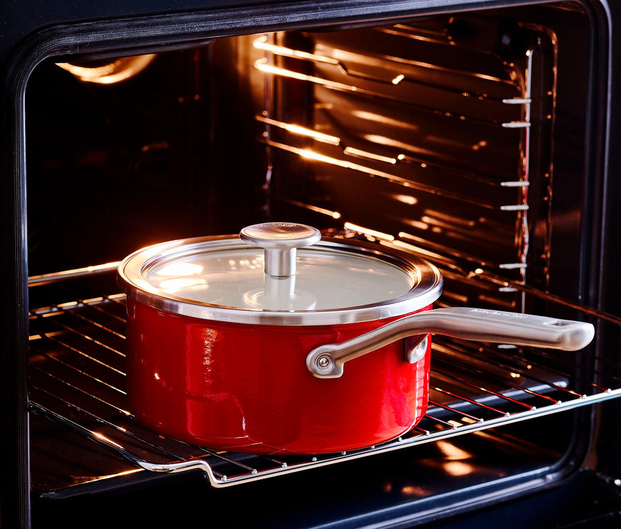 Rote KitchenAid Steel Core Emaille Stielkasserolle mit Deckel im Ofen.
