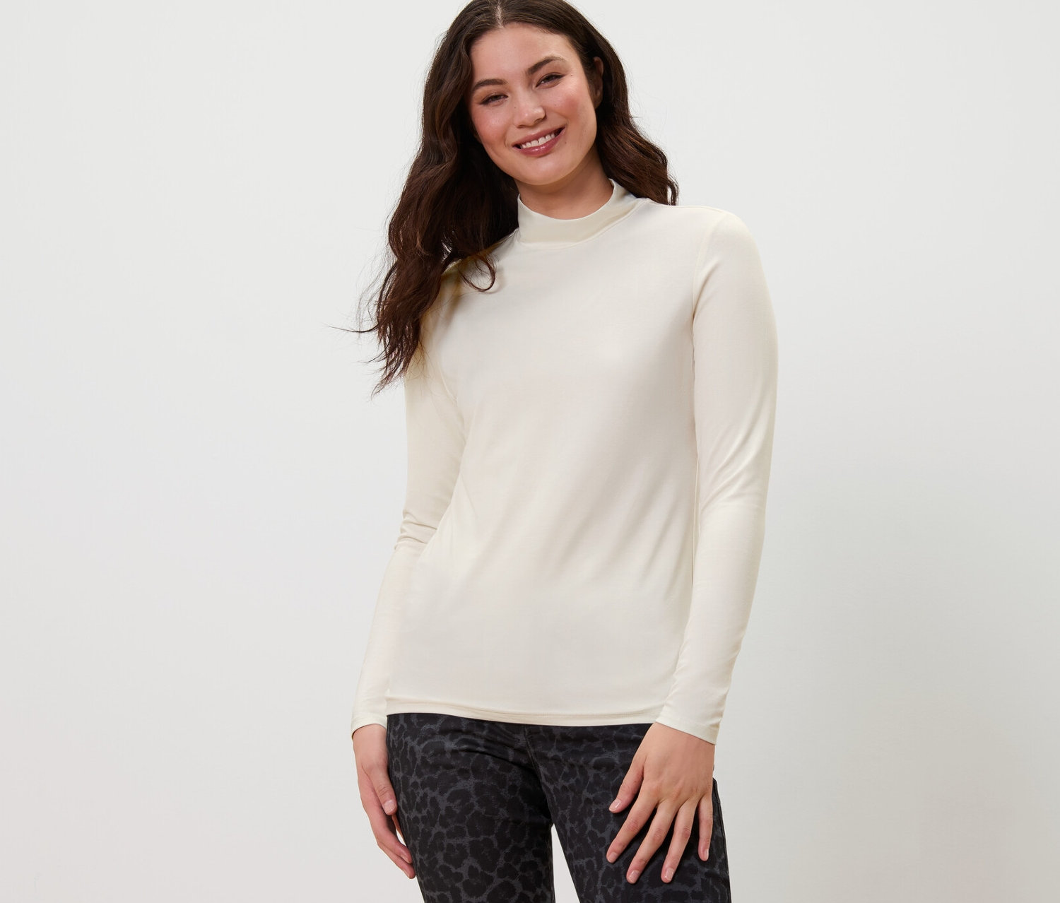 Frau posiert in Blusenshirt mit Stehkragen und gemusterter Hose.