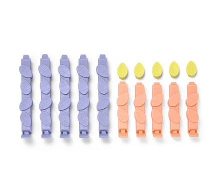 Fünfzehn Aromaclips in Lila und Pfirsichfarbe und gelbe Blätter.