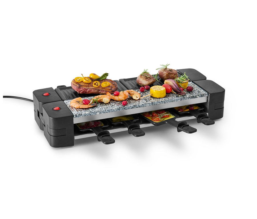 Ein klappbarer Raclette-Grill mit Fleisch, Garnelen und Gemüse oben und Pfannen unten.