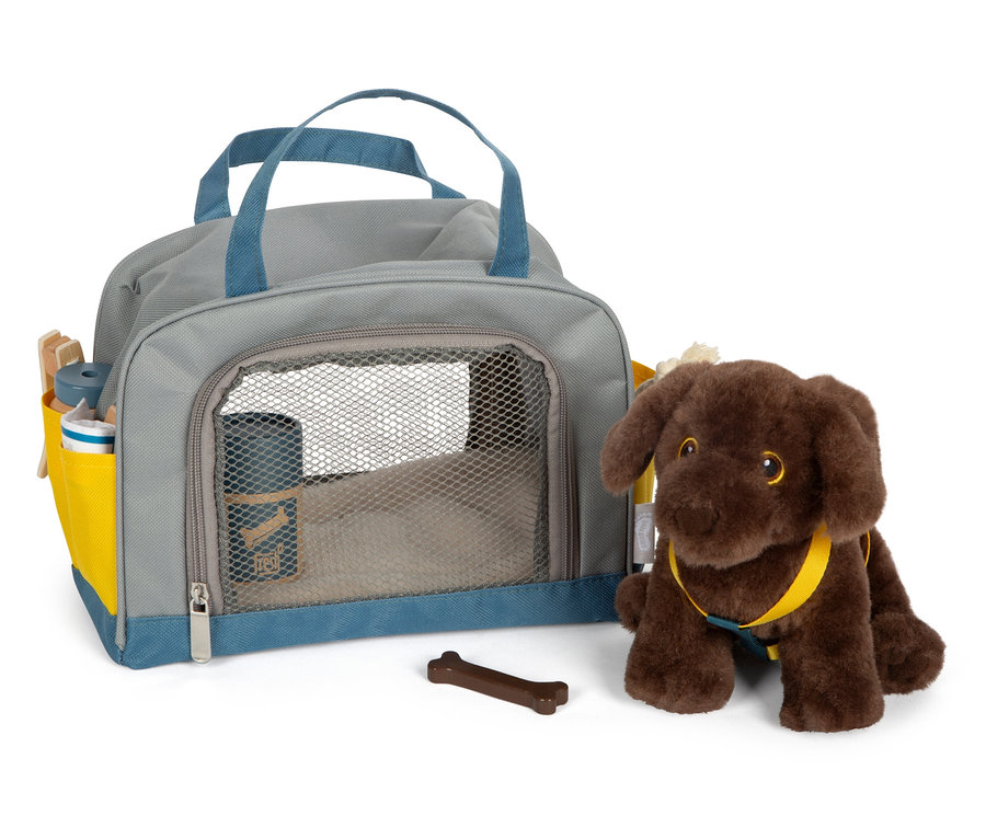 Ein brauner Plüschhund sitzt neben einer grauen Tasche mit blauen Details und einem braunen Knochen.
