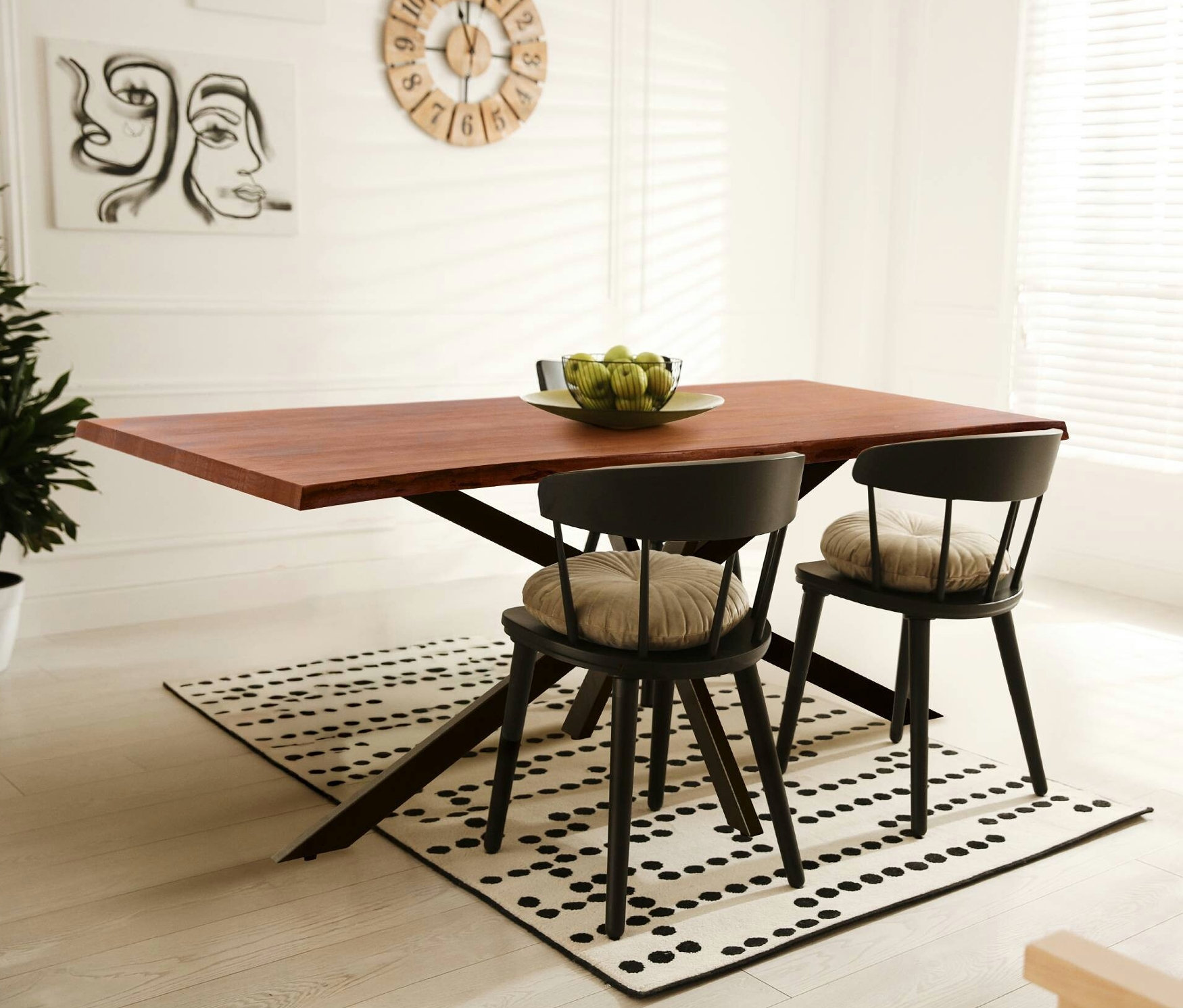 Ein dunkelbrauner Eglo Tisch mit gekreuzten Beinen und zwei schwarze Stühle mit beigen, runden Sitzkissen auf einem weißen Teppich mit schwarzen Punkten.