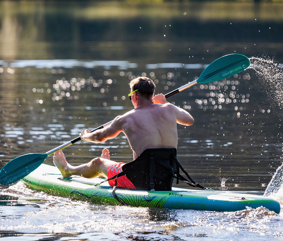 Mann paddelt mit SUP-Sitz Spinera auf einem See.