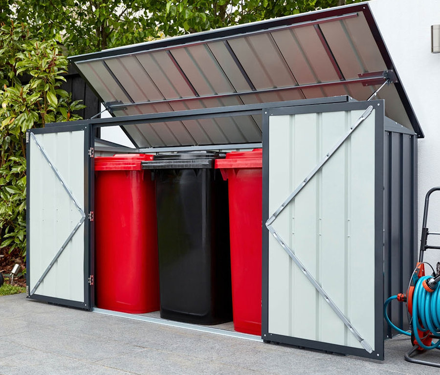 Geöffnete graue Gerätebox mit zwei roten und einer schwarzen Mülltonne darin, Rasenmäher und Schlauch daneben.