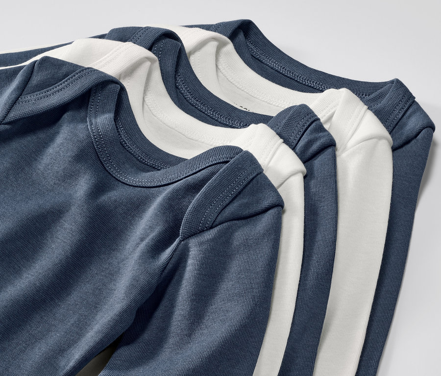 Detailansicht von fünf blauen und weißen Baby-Bodys mit Mitwachsfunktion.