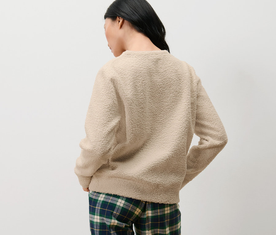 Frau von hinten trägt einen Kuschel-Sweater und karierte Hosen.