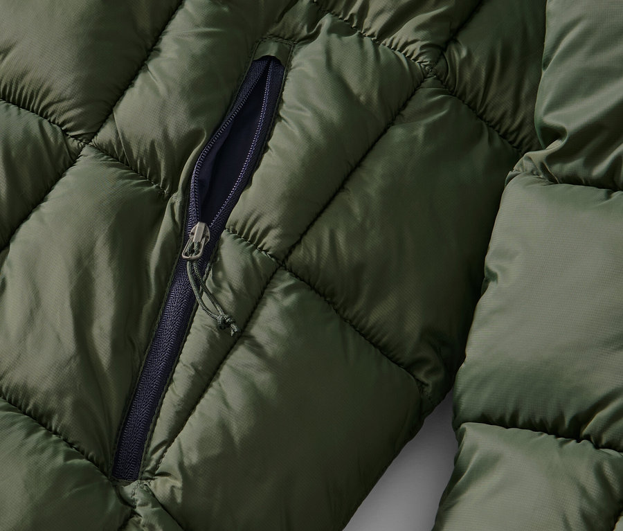 Detailansicht einer khaki Steppjacke mit teilweise geöffnetem Reißverschluss.