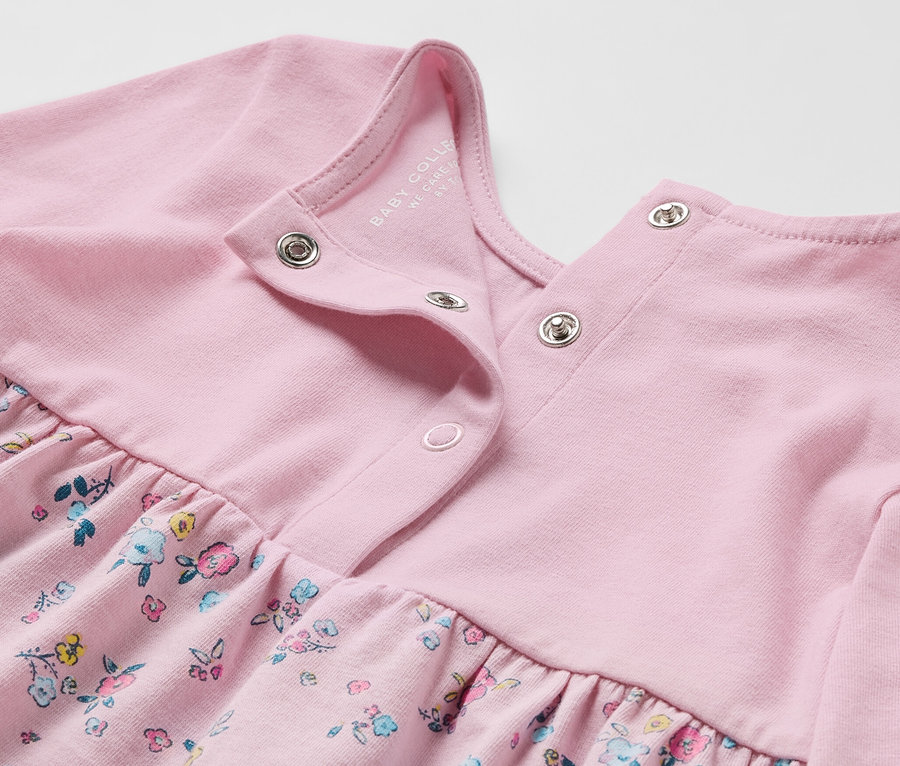 Detailansicht eines rosa Baby-Jerseykleids mit Blumendruck.