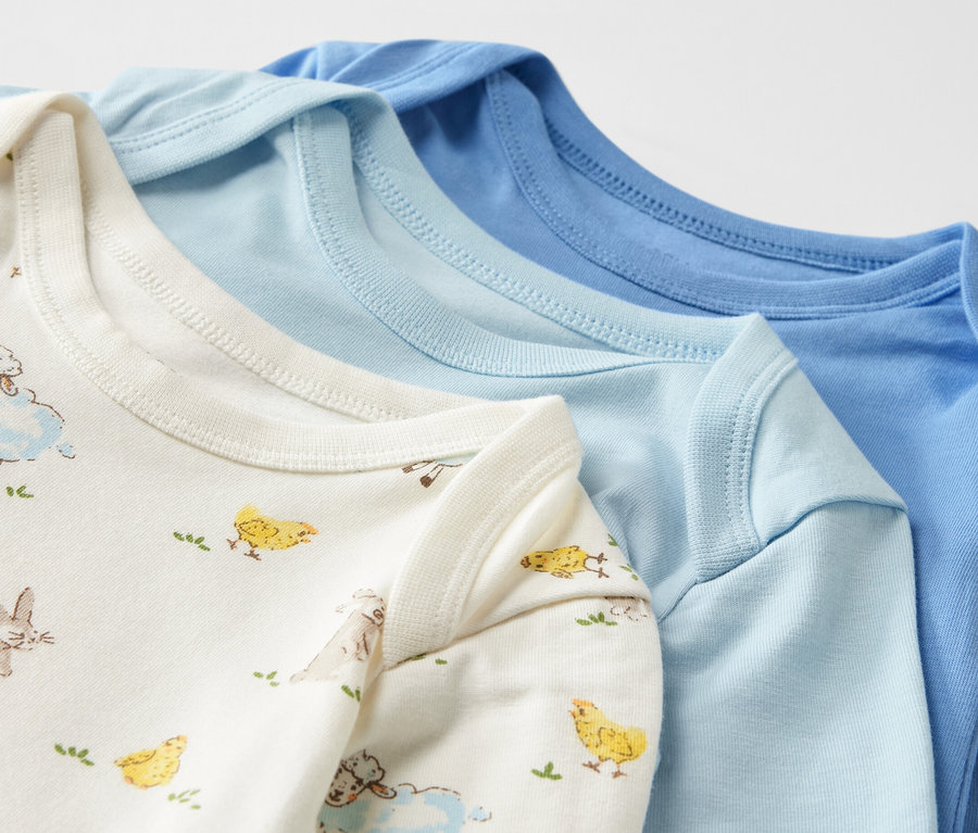 Detailansicht von drei blauen Baby-Bodys mit Mitwachsfunktion.