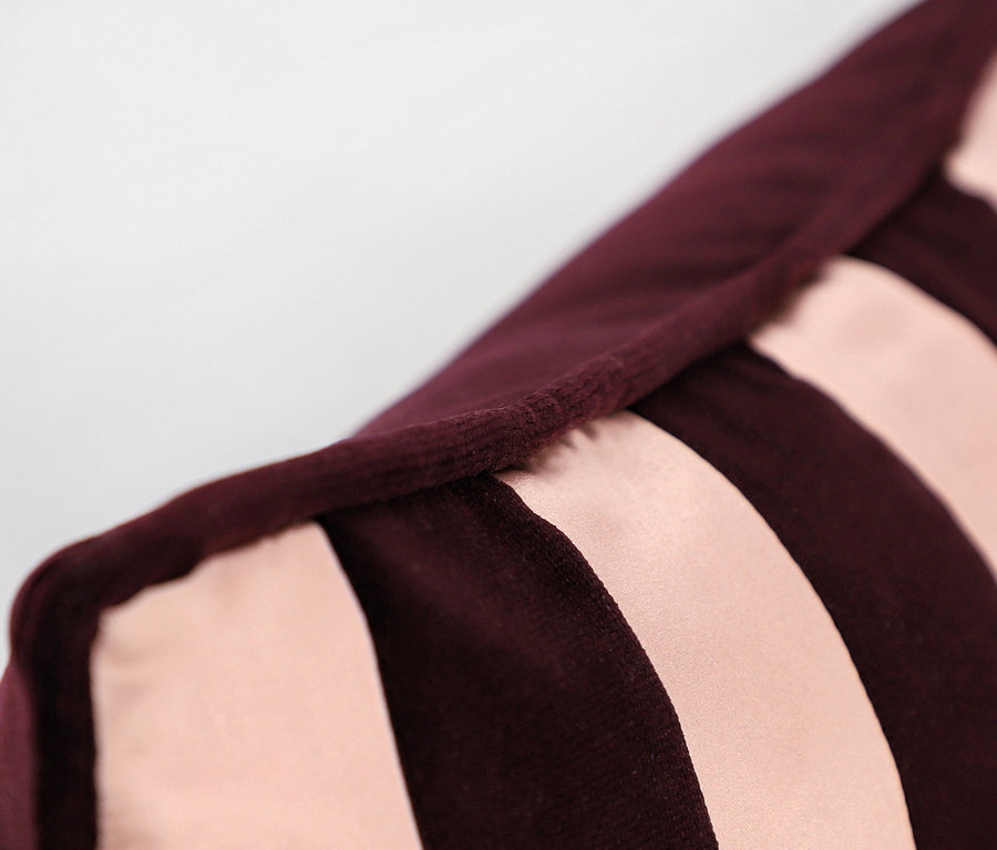 Detail einer Kissenecke mit bordeauxroten und rosa Streifen.