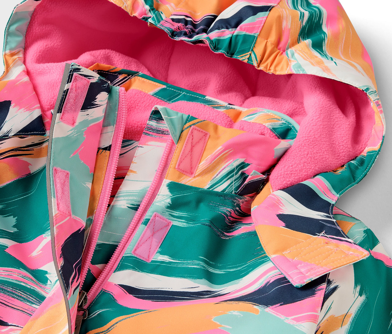 Detail einer Kapuzenjacke mit buntem Muster und rosa Futter.