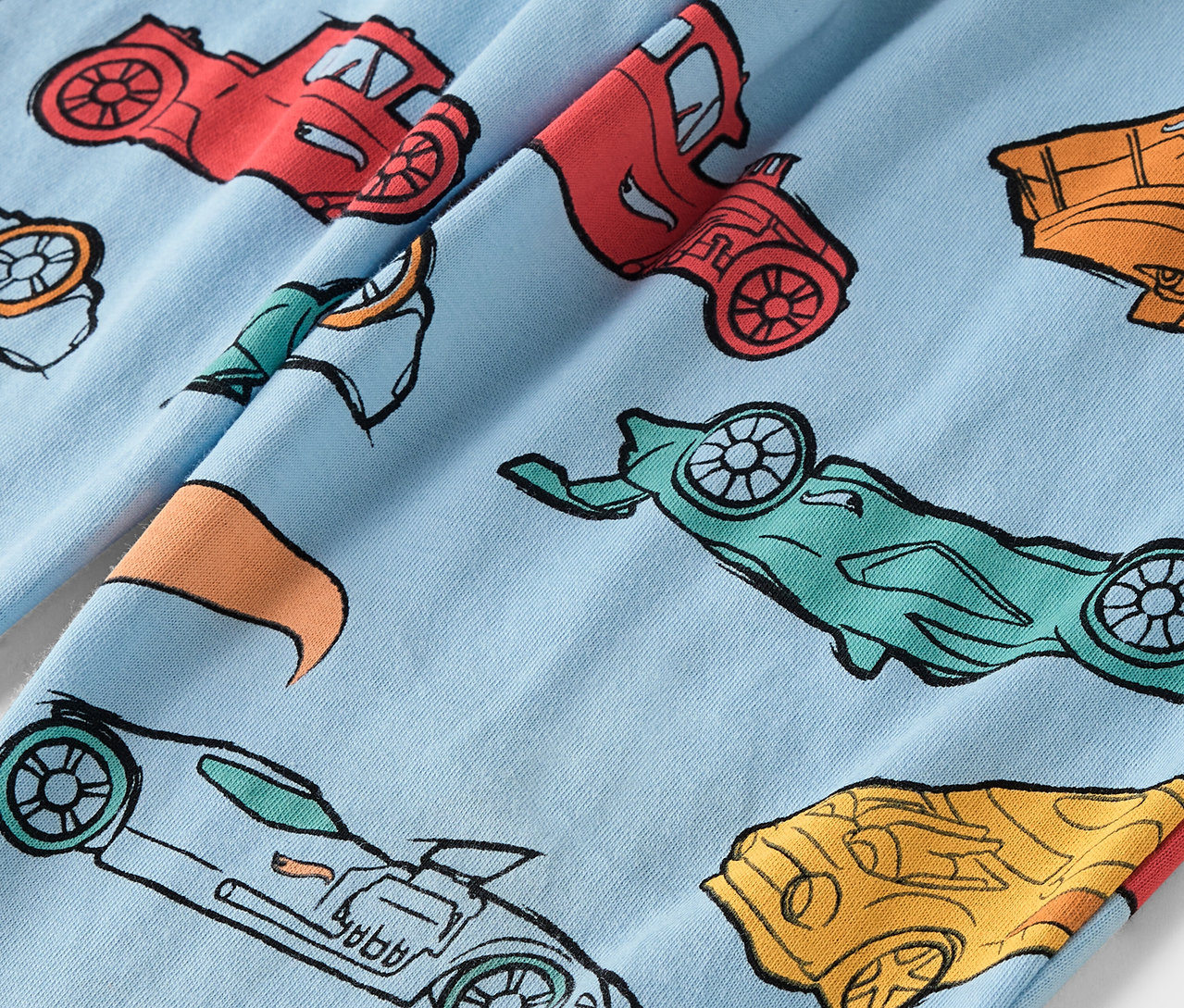 Hellblauer Stoff mit einem Aufdruck von bunten Autos.