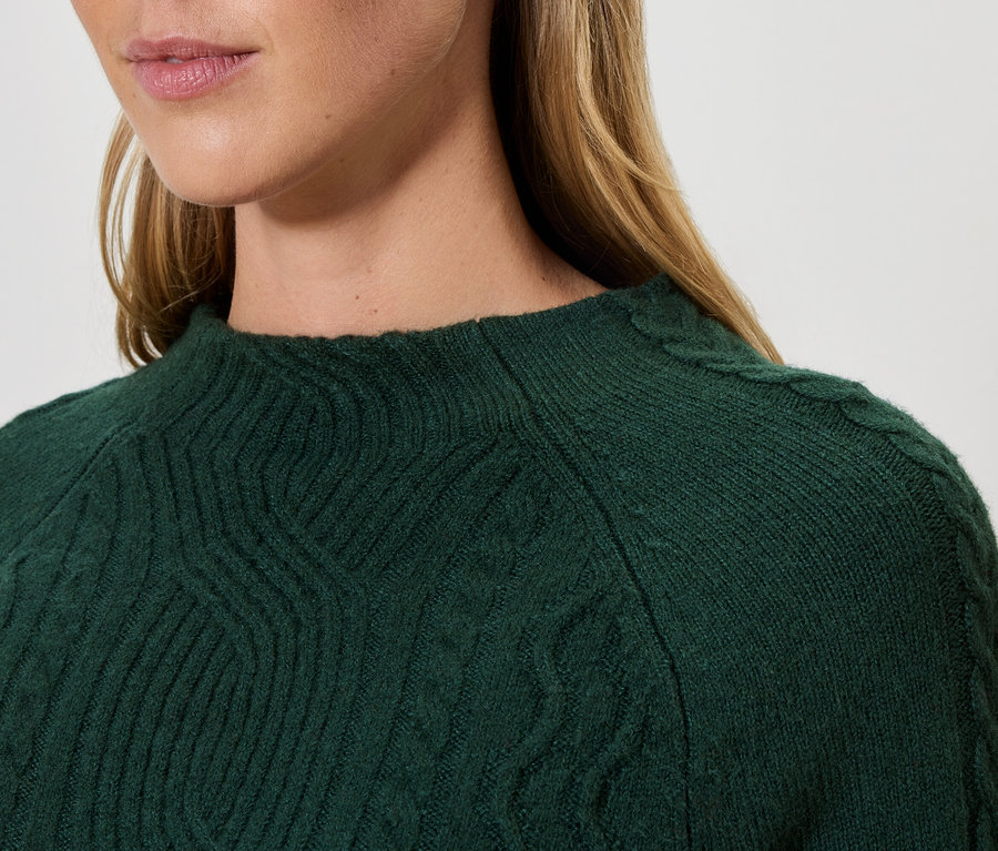 Detailaufnahme einer Frau, die einen grünen Strickpullover trägt.