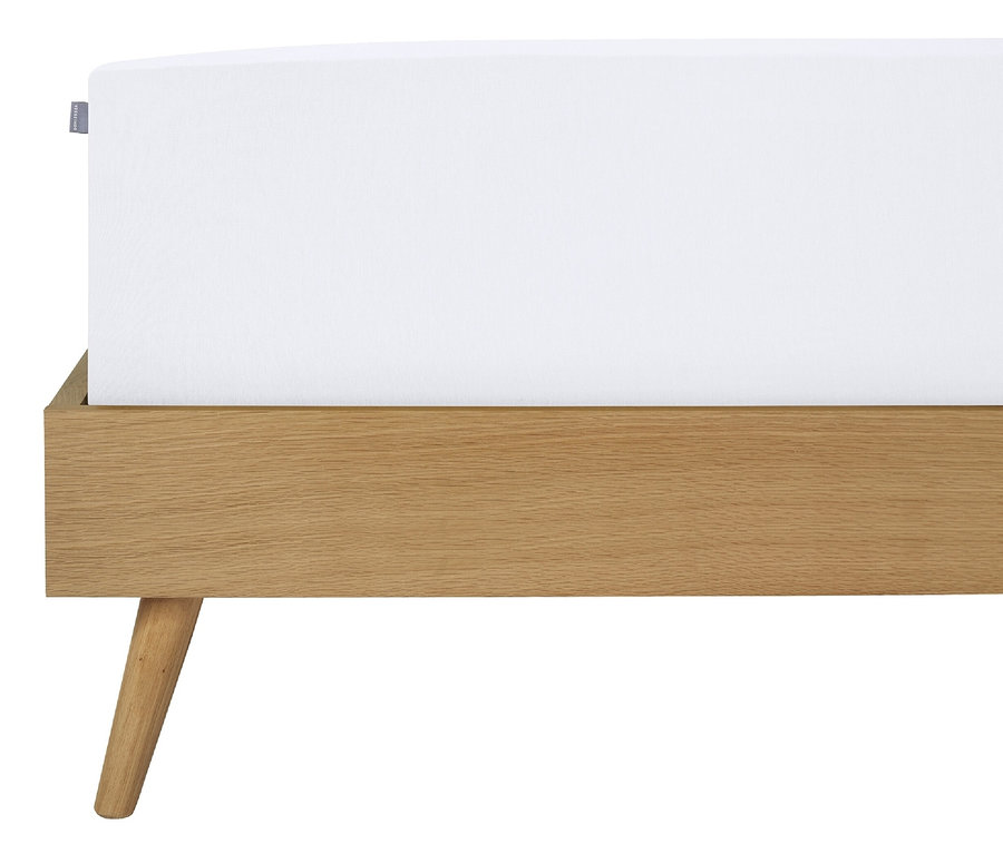 Detailansicht eines weißen SCHIESSER Edeljersey-Spannbettlakens »Jessi« auf einem Bett mit Holzrahmen.