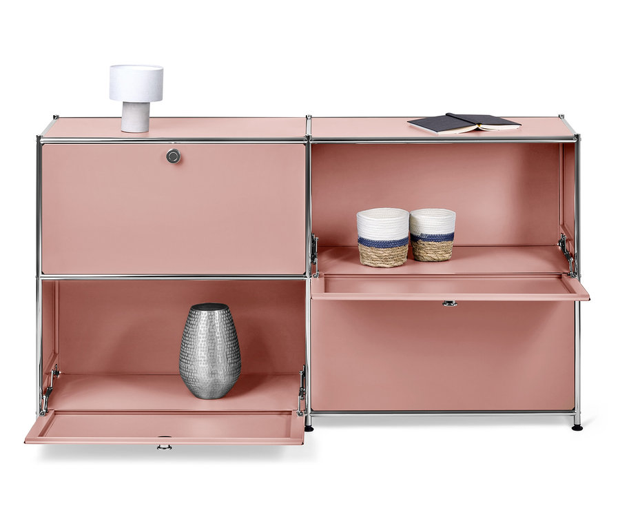 Ein rosa Schrank mit offenen Türen, auf dem eine Lampe, eine Vase, zwei Körbe und ein Notizbuch stehen.