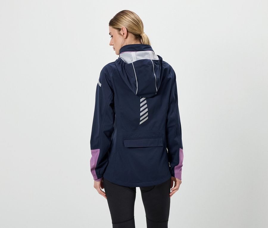 Von hinten ist eine Frau in einer dunkelblauen Jacke mit Kapuze, schwarzen Hosen und lila Ärmeln zu sehen.