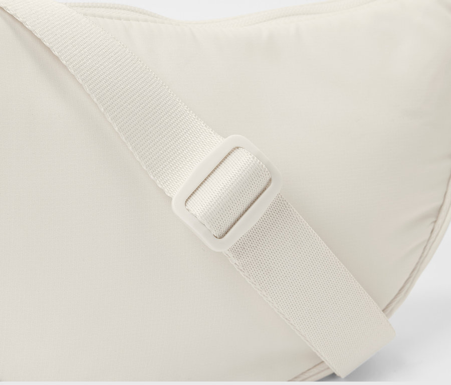 Detailaufnahme einer weißen Umhängetasche mit verstellbarem Träger.
