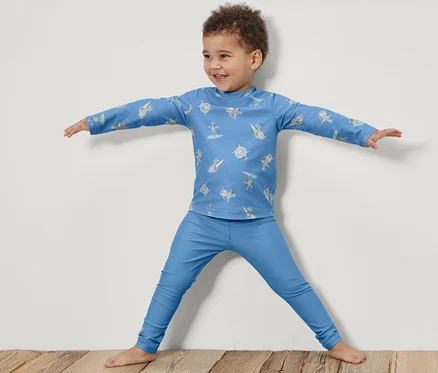 Ein Junge steht mit ausgestreckten Armen und trägt Kinder-Badeleggings mit UV-Schutzfaktor 80.
