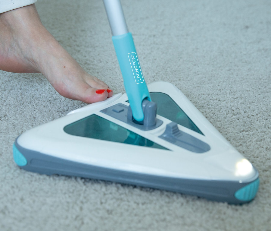 Frau benutzt Akkubesen auf Teppich.