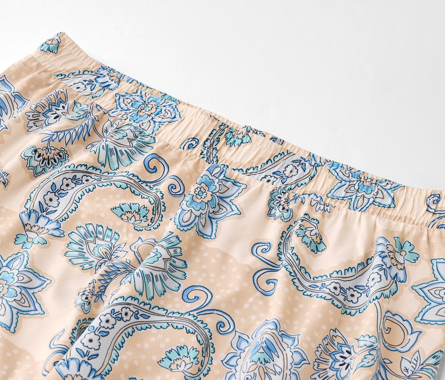 Nahaufnahme von hellbeigen Hosen mit blauem Blumenmuster und elastischem Bund.