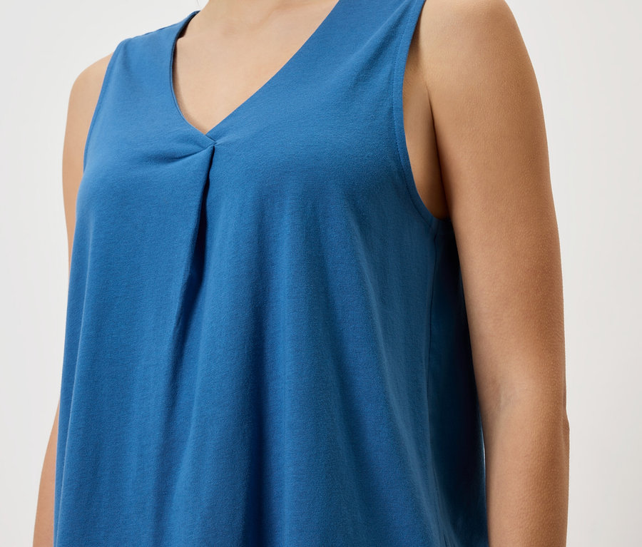 Nahaufnahme einer Frau, die ein blaues ärmelloses Top trägt.