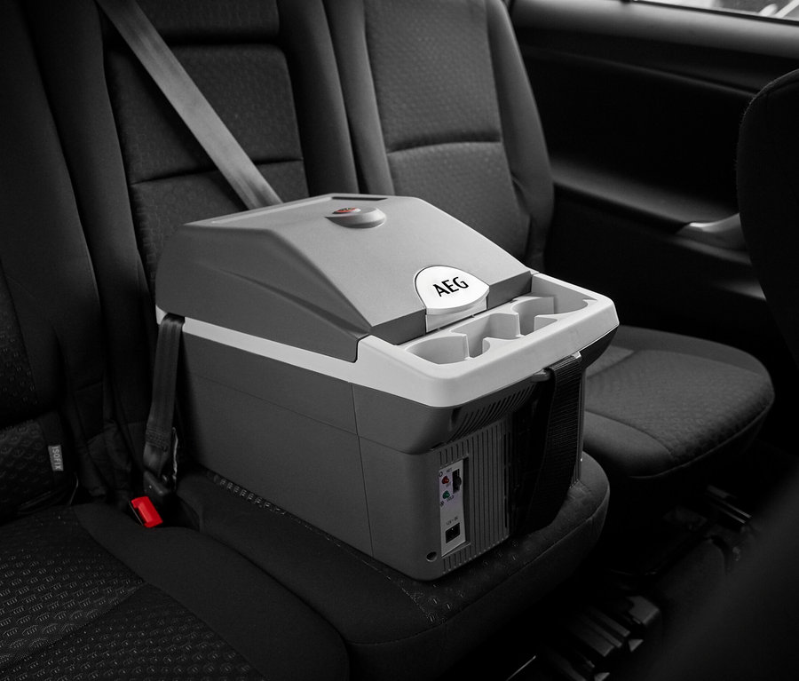 Graue und weiße AEG Bordbar »BK16« auf dem Rücksitz eines Autos, mit einem Sicherheitsgurt befestigt.