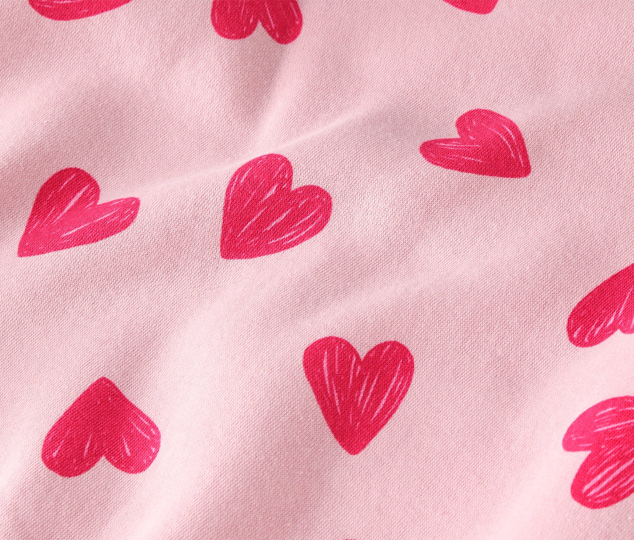 Nahaufnahme eines hellrosa Stoffes mit rotem Herzmuster.
