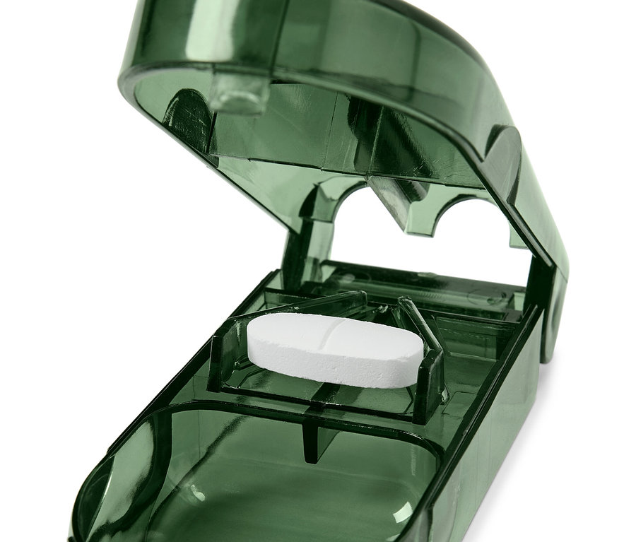 Eine weiße Tablette in einem offenen, durchsichtigen, grünen Tablettenteiler.