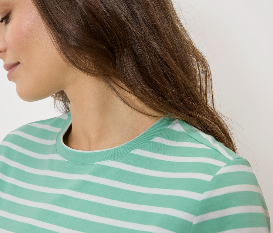 Nahaufnahme einer Frau mit braunen Haaren, die ein grün-weiß gestreiftes T-Shirt trägt.