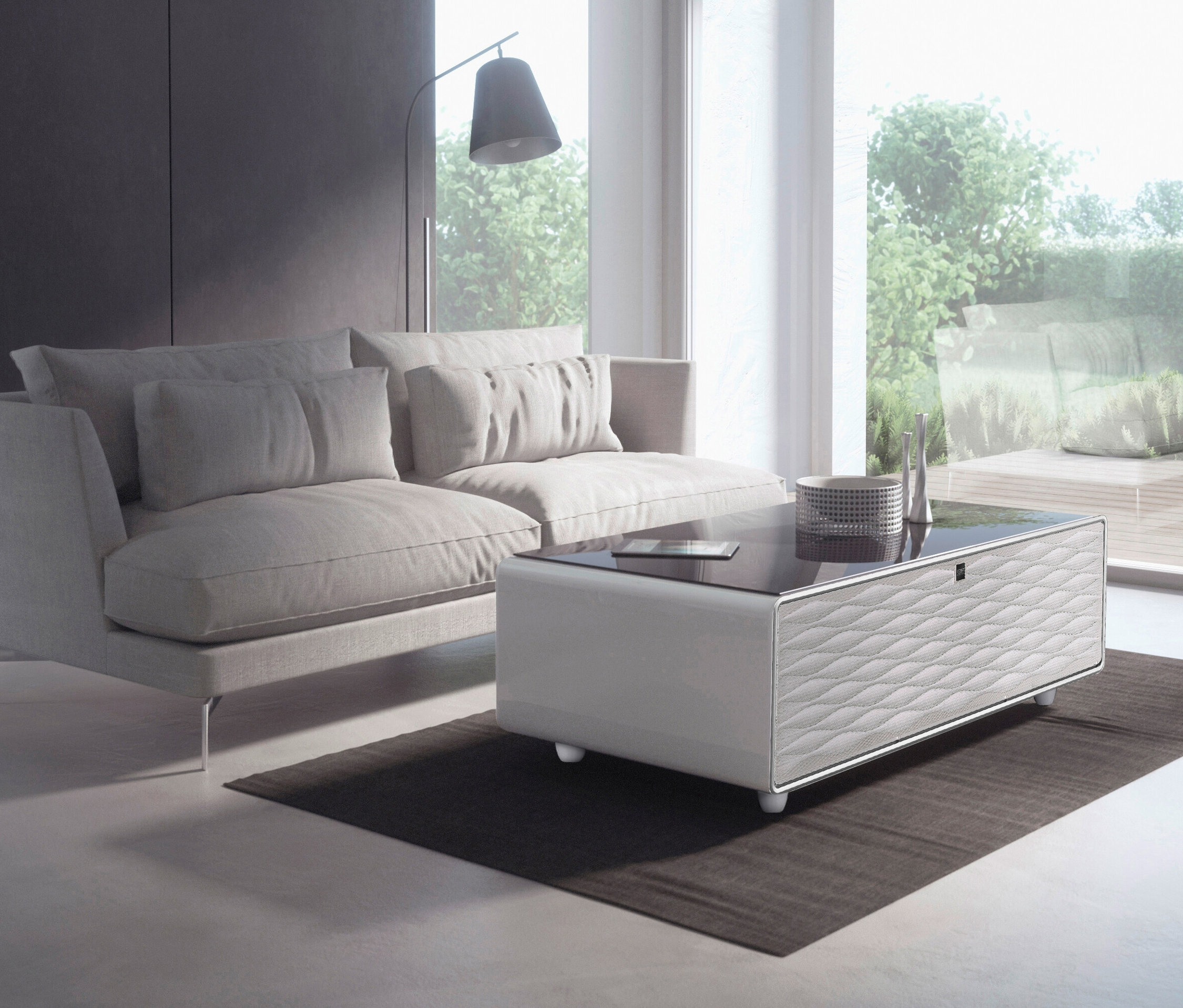 Wohnzimmer mit grauem Sofa und weißem Caso Sound & Cool Tisch.