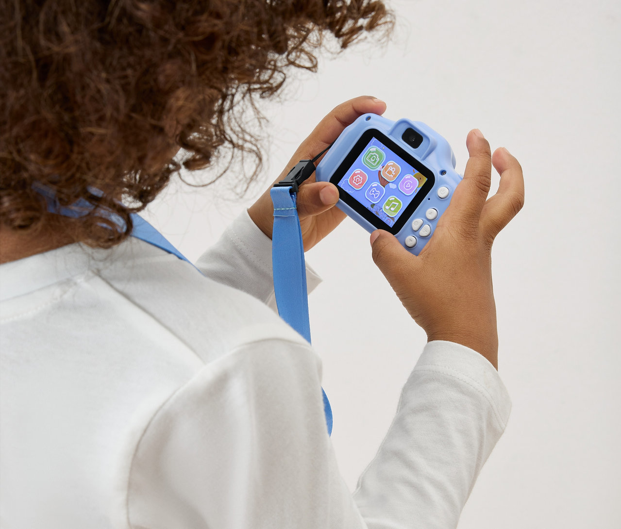 Kind hält eine hellblaue Spielzeugkamera mit blauem Trageband vor sich.