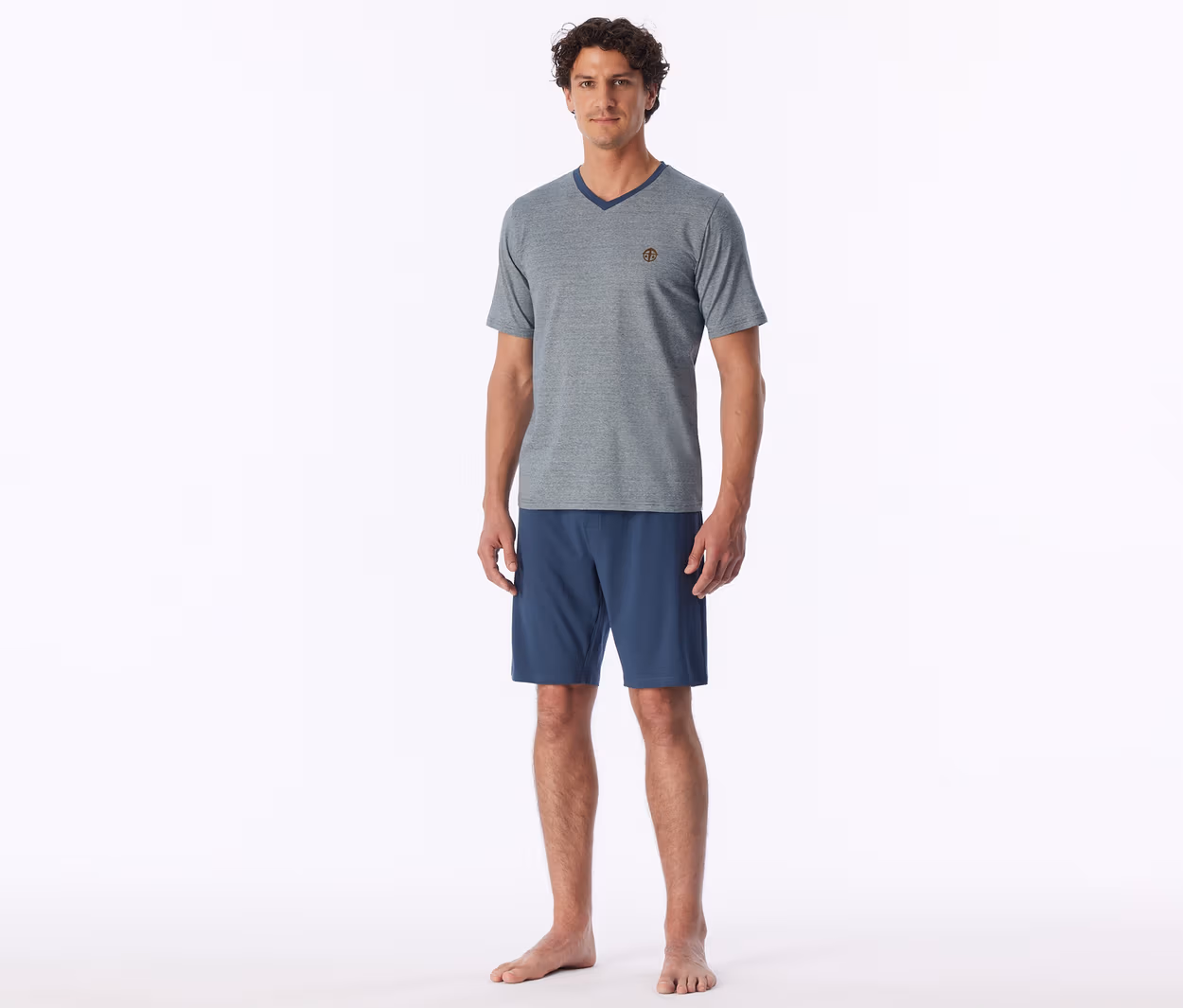 Mann steht barfuß und trägt ein graues V-Ausschnitt-T-Shirt und blaue Shorts.