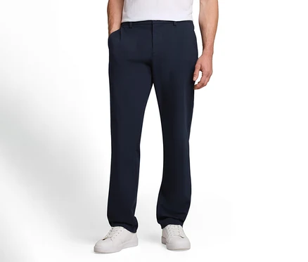 Mann in dunkelblauer Hose und weißen Sneakern, eine Hand in der Hosentasche.
