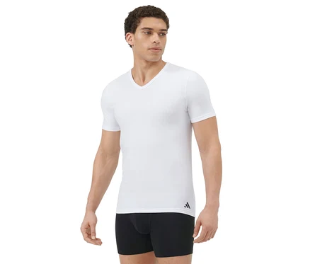 Mann in einem weißen V-Ausschnitt-T-Shirt und schwarzen Boxershorts, steht und blickt nach rechts vor weißem Hintergrund.