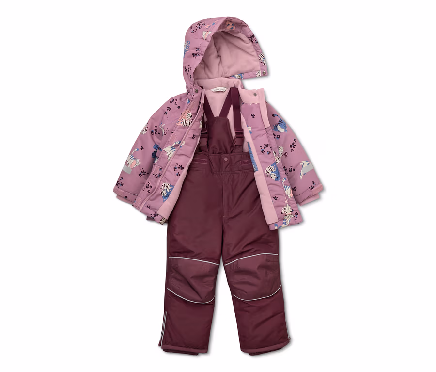 Lila Kinderjacke mit Katzenmuster und offener Kapuze über einer weinroten Latzhose.