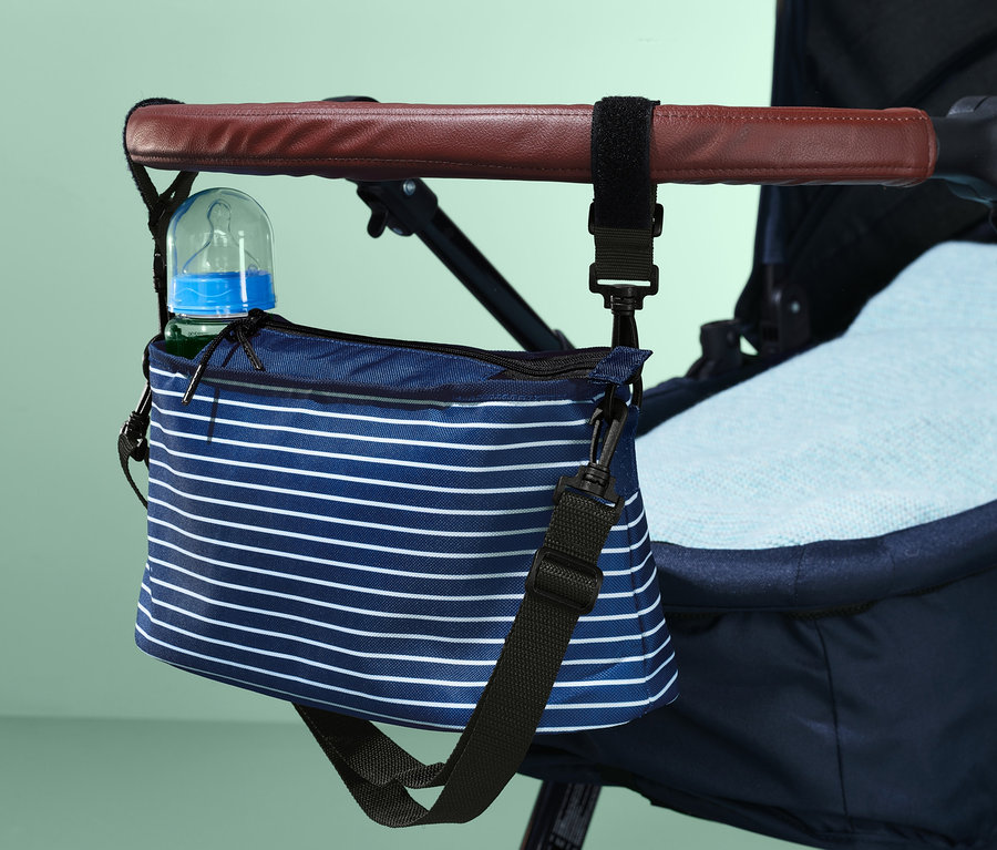Ein blau-weiß gestreifter Organizer für Kinderwagen, der mit einer Flasche am Griff eines Kinderwagens befestigt ist.