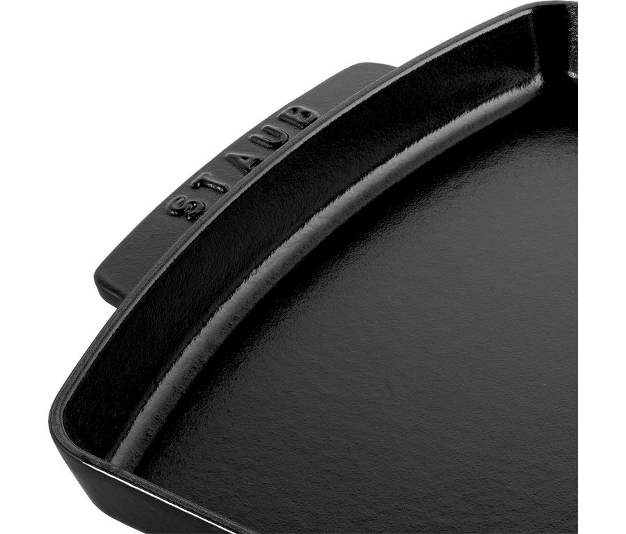 Schwarze gusseiserne Pfanne mit dem eingeprägten Schriftzug „STAUB“ auf dem Griff.