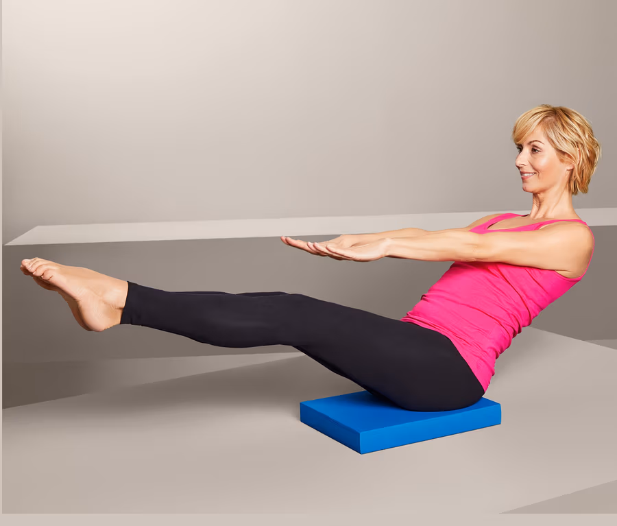 Frau macht Sit-ups auf einem Balance-Pad.